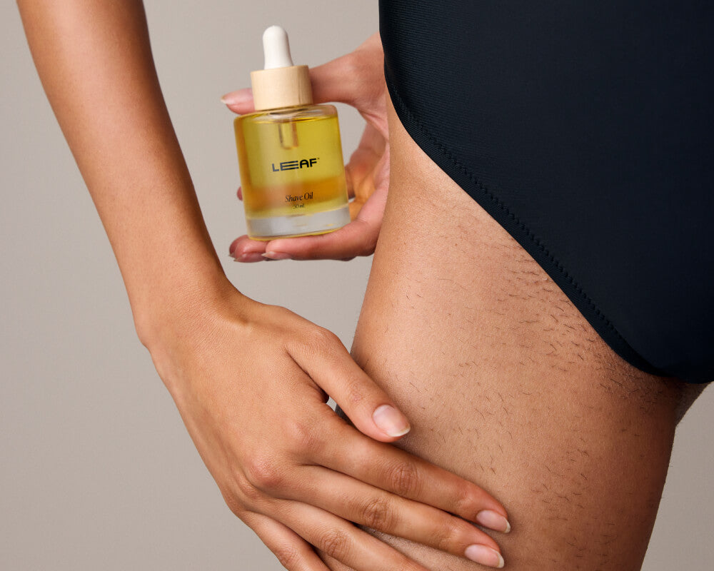 Woman touches her groin while holding shave oil in the other hand