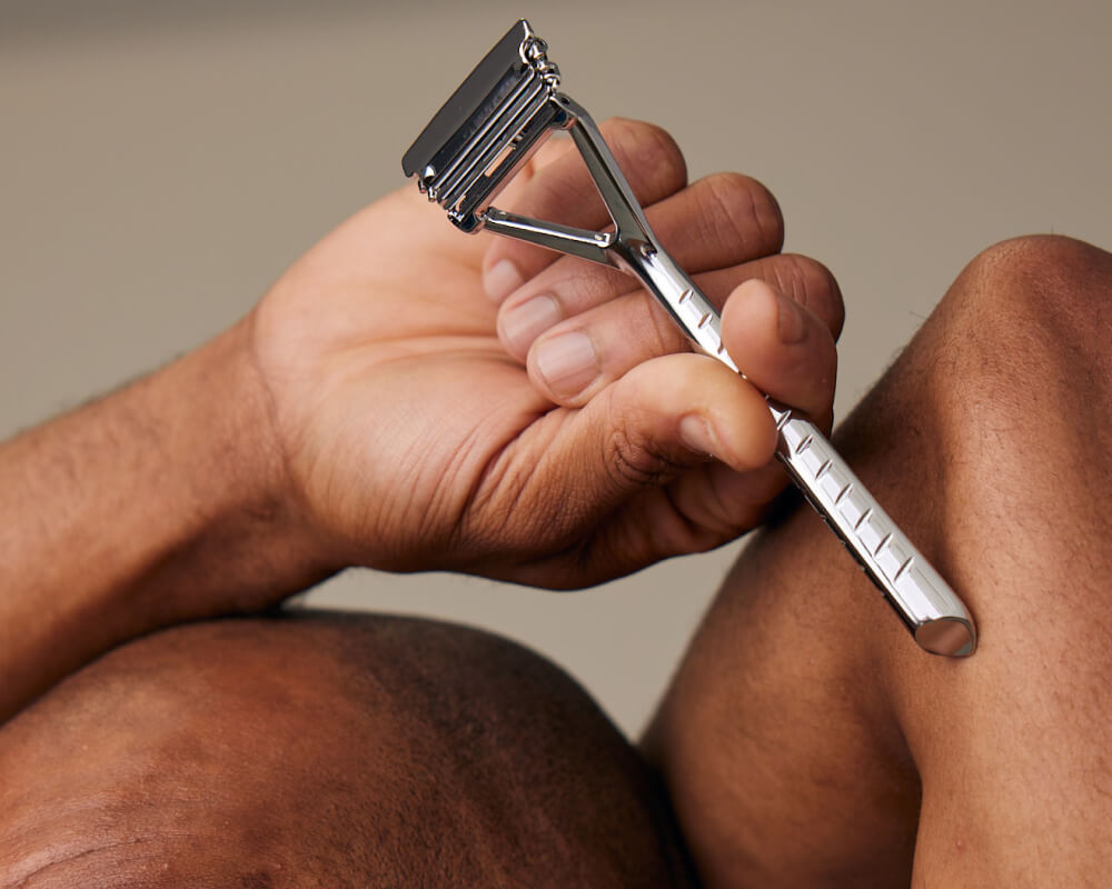 Man holds leaf razor up to his other arm