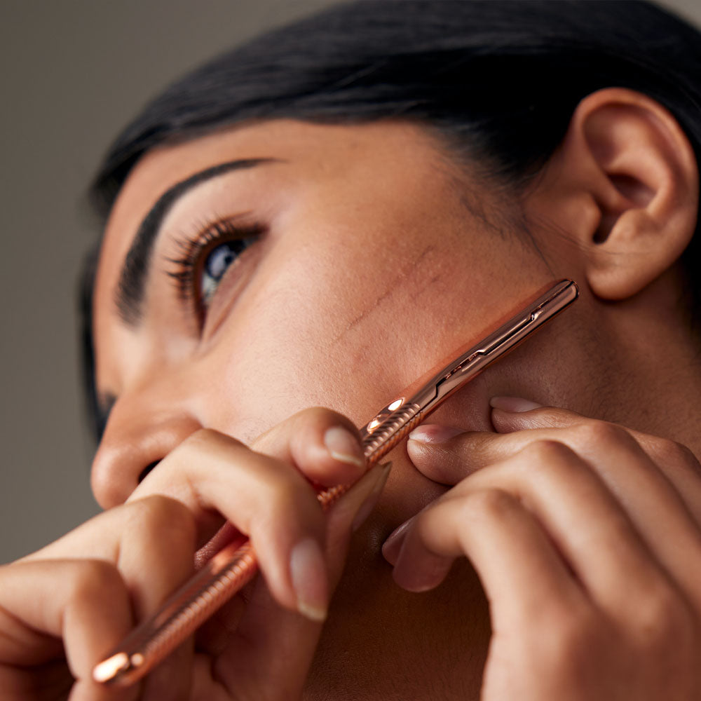 Woman uses the dermaplaner on her cheek