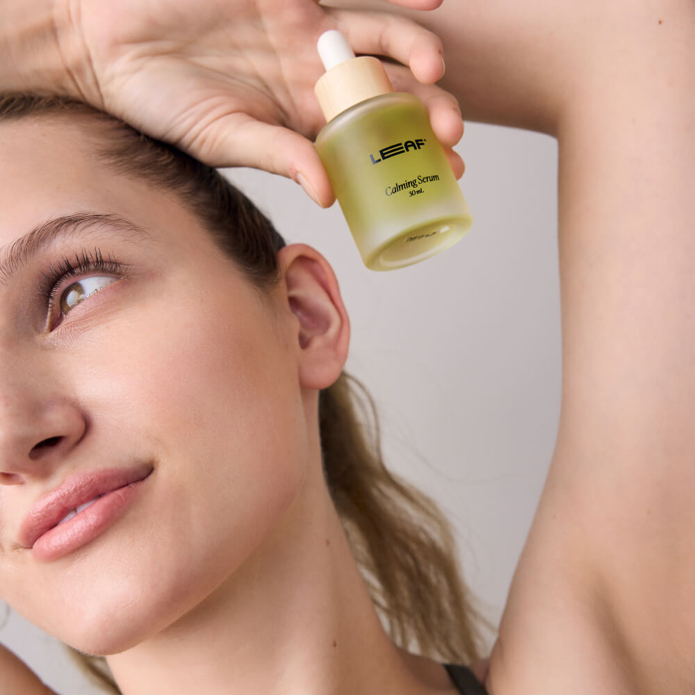 Woman holds calming serum near her face