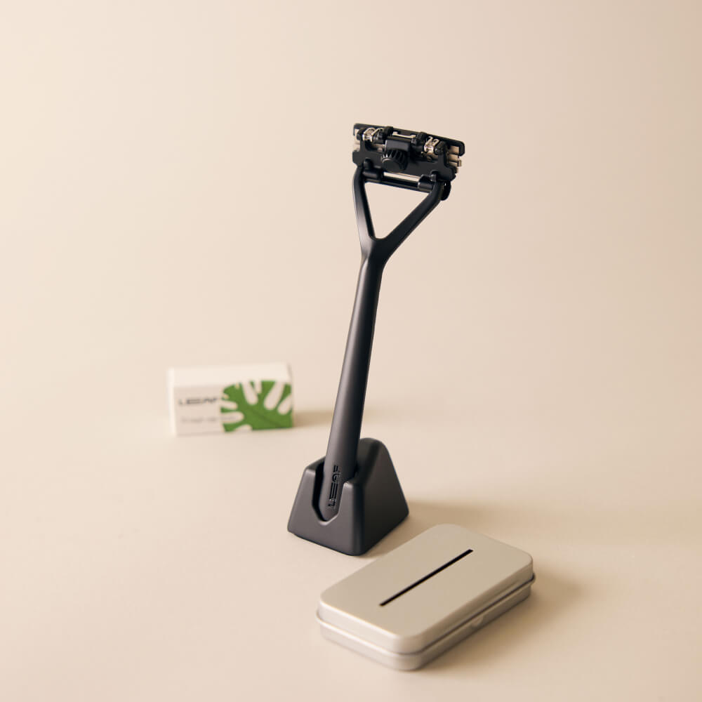 The black Leaf razor kit with the razor, stand, package of blades, and recyclable tin 