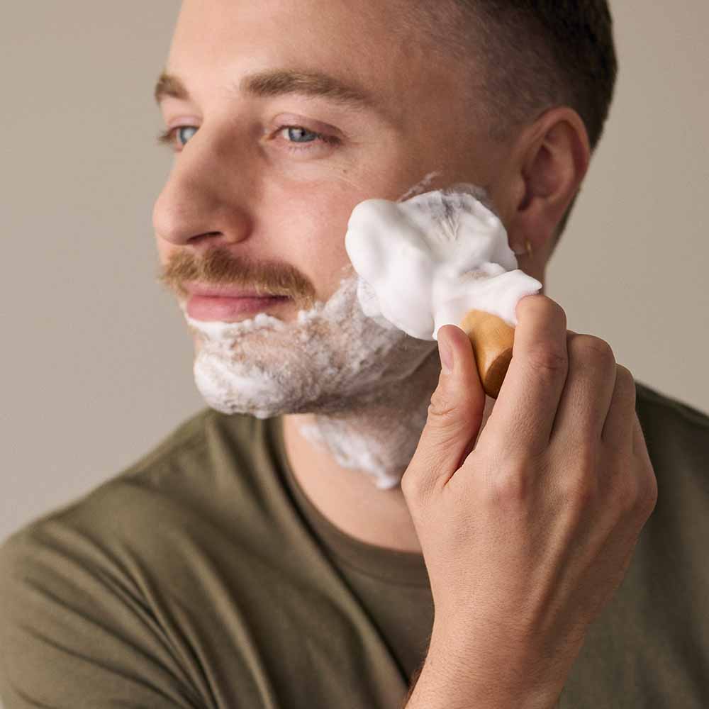 Man applies shave soap on his chin and cheek area